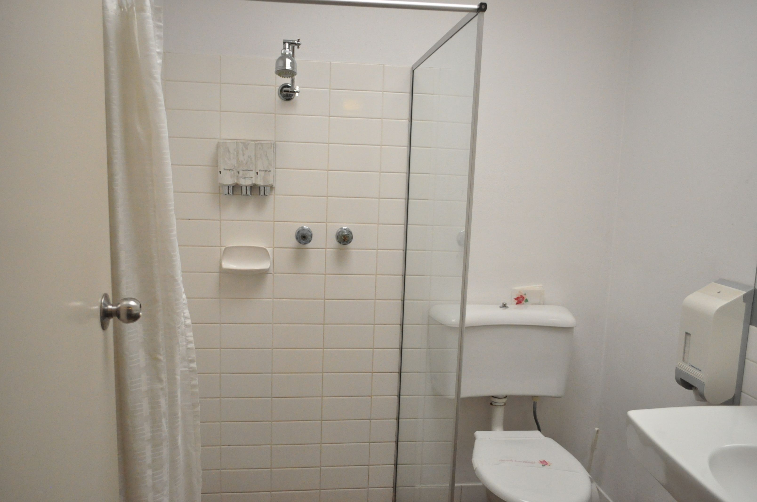 A bathroom with a shower, toilet, and hand dryer.