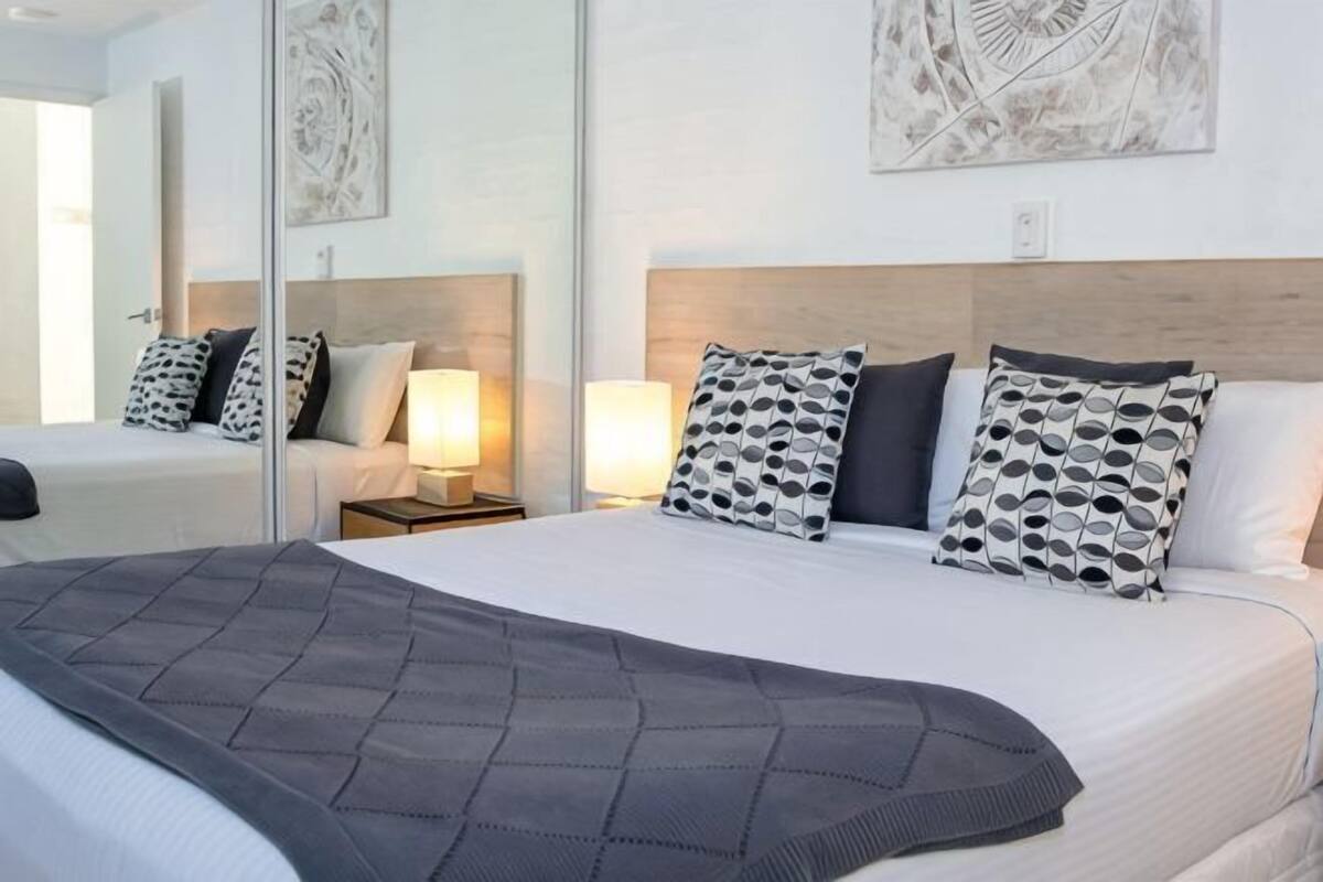 Una habitación de hotel con una cama grande, mesitas de noche con lámparas y obras de arte en las paredes.