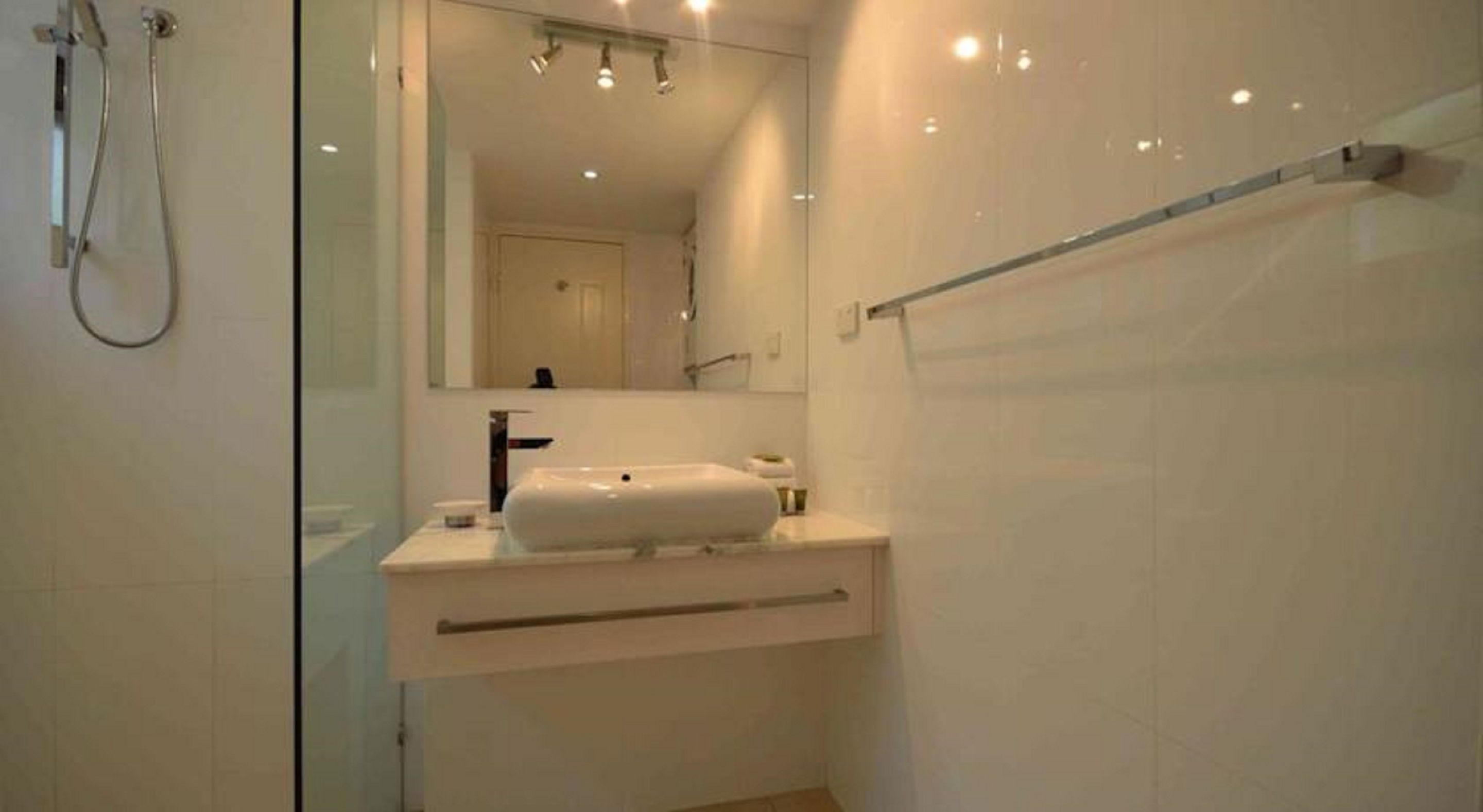 Un baño moderno con cabina de ducha de vidrio, un lavabo blanco y un espejo grande.