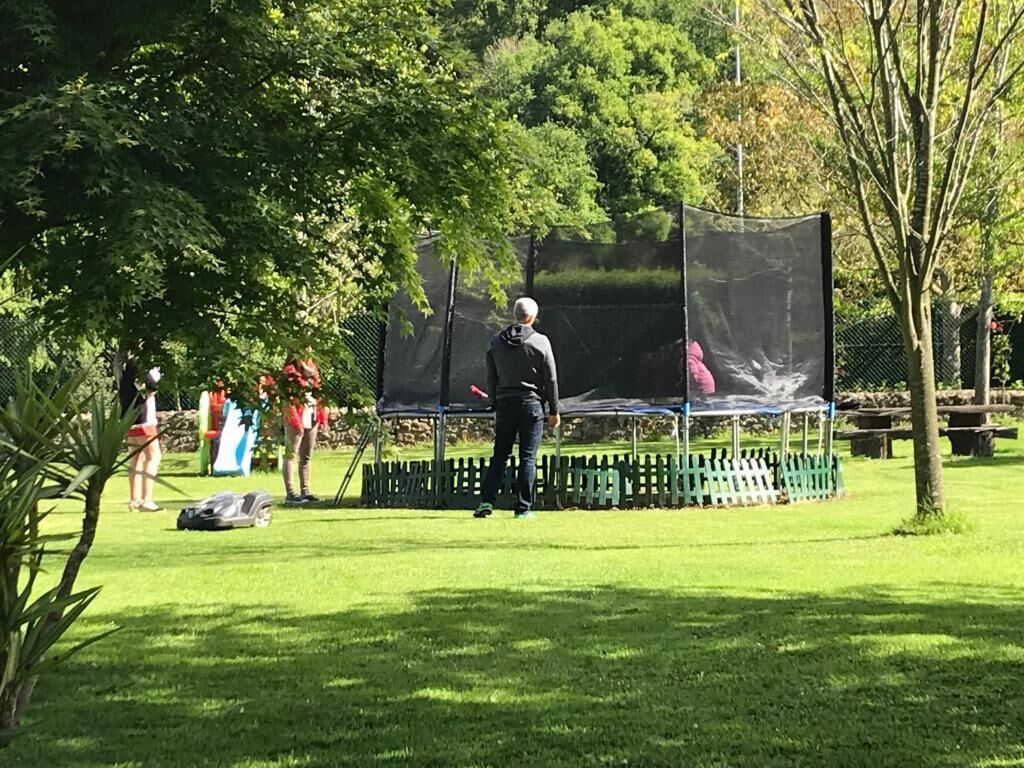 Een park met een trampoline en een omheind gebied.