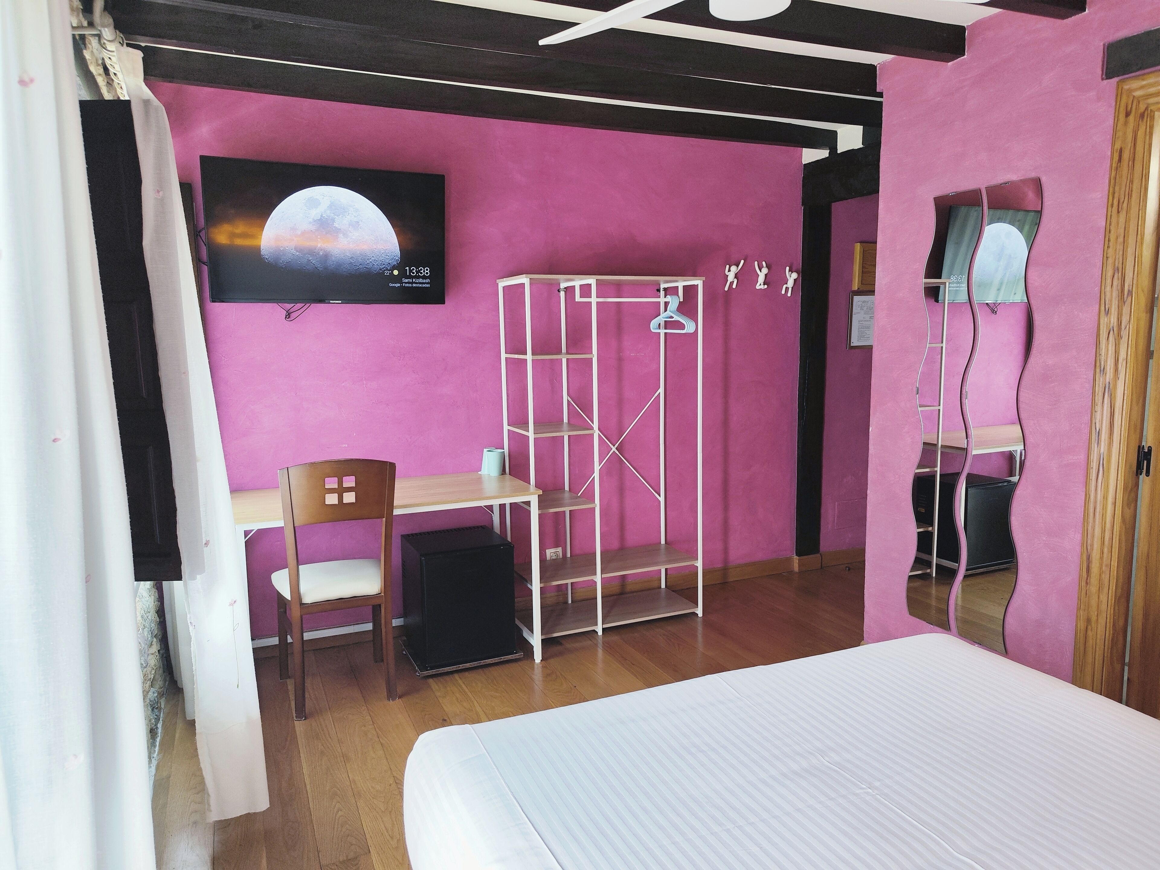 A room with a bed, a desk, a chair, a wardrobe, and a mirror.