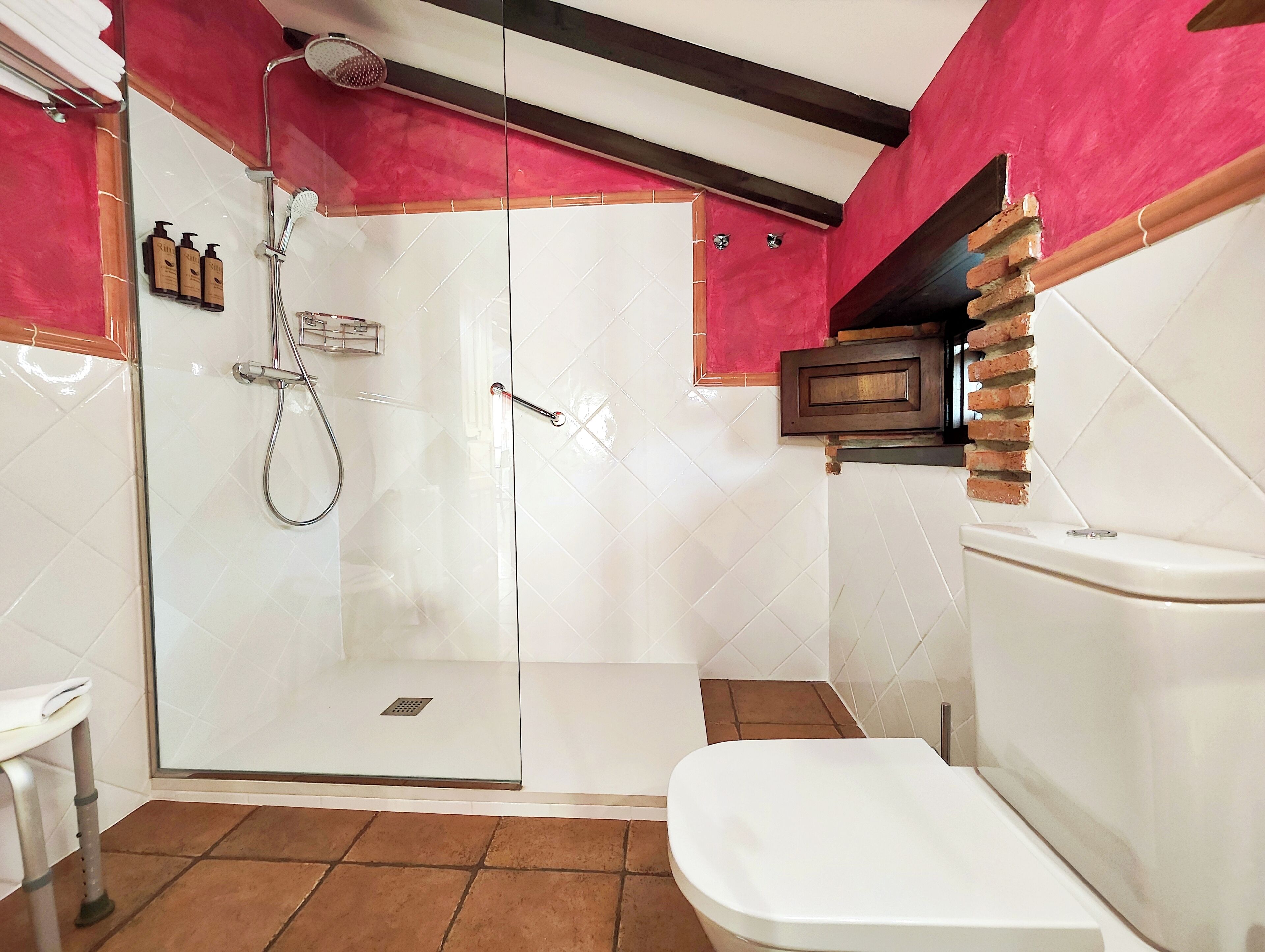 Een badkamer met een douchecabine van glas, een wit toilet en een wastafel.