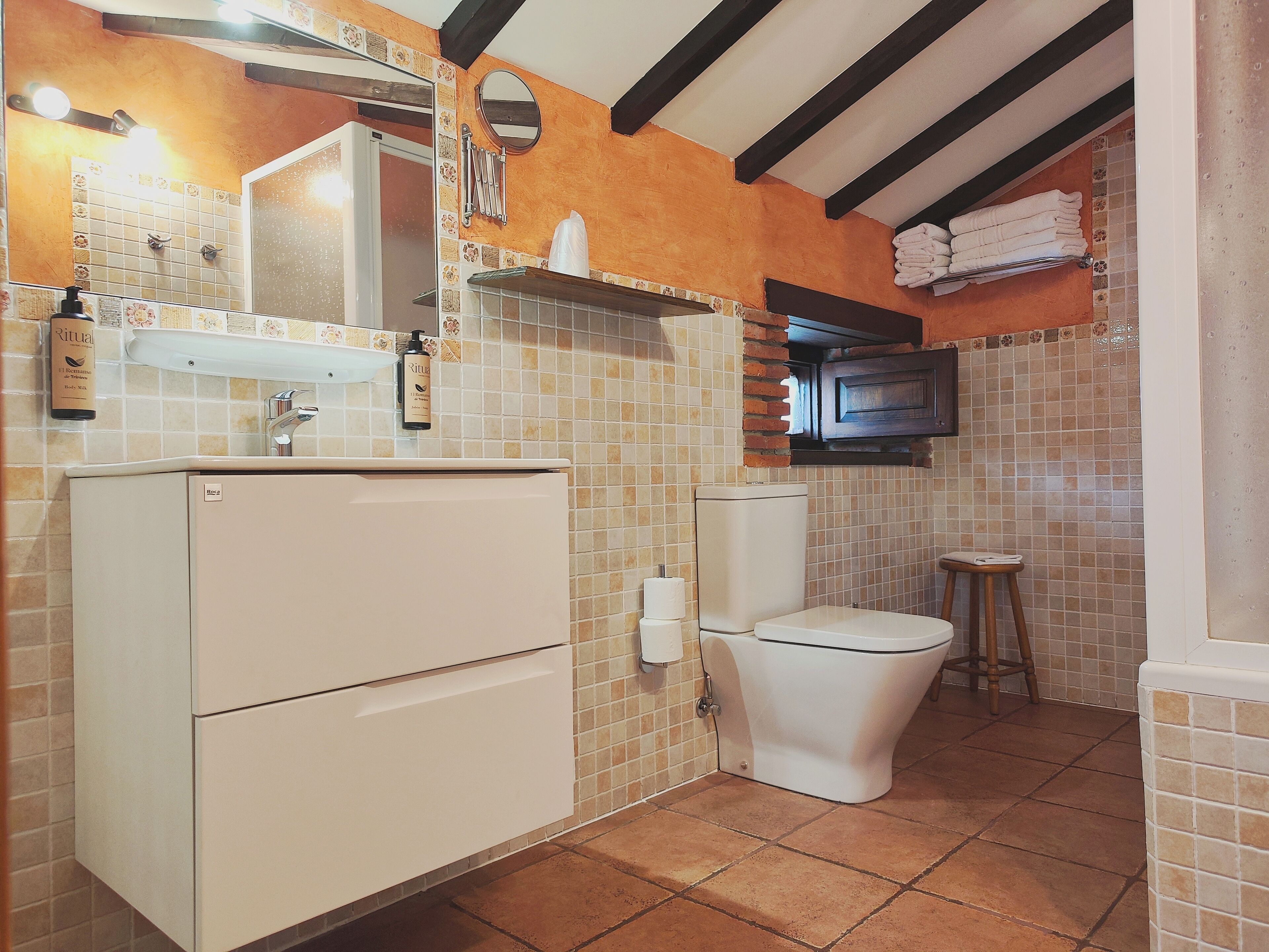 Een kleine badkamer met toilet, wastafel en een klein krukje.