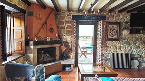 Een rustiek interieur met zichtbare balken, een stenen openhaard en uitzicht naar buiten.