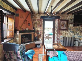 Un interior rústico con vigas a la vista, una chimenea de piedra y vistas al exterior.