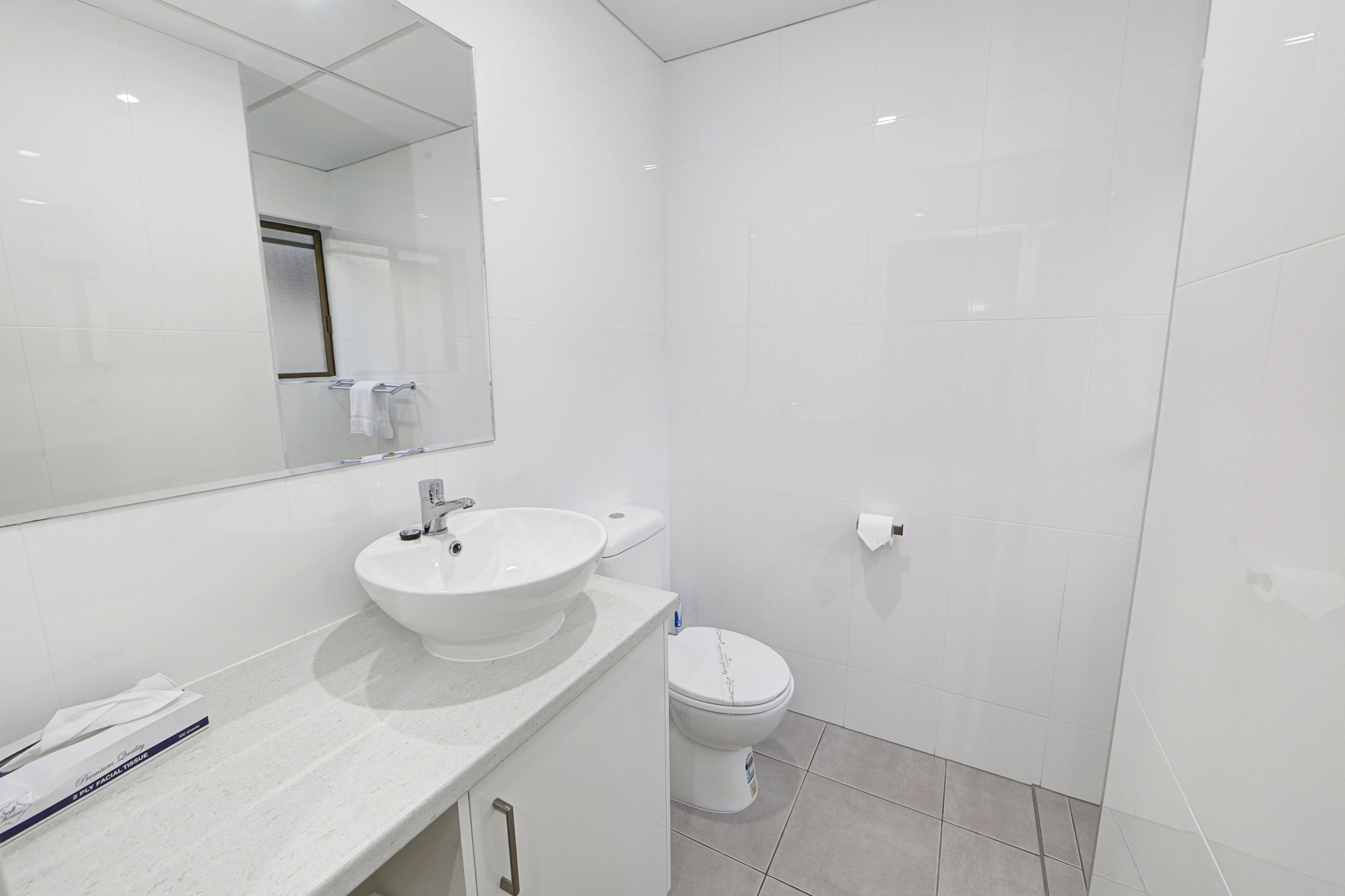 A modern bathroom with a white sink, toilet, and mirror.