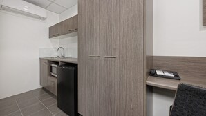 Una cocina moderna con microondas integrado, lavavajillas y un armario de madera.