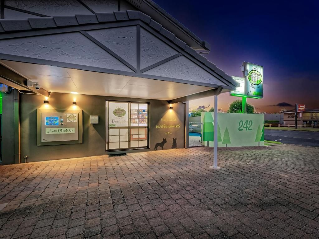 A building with a brick facade, a framed welcome sign, and a green sign with the number 242.