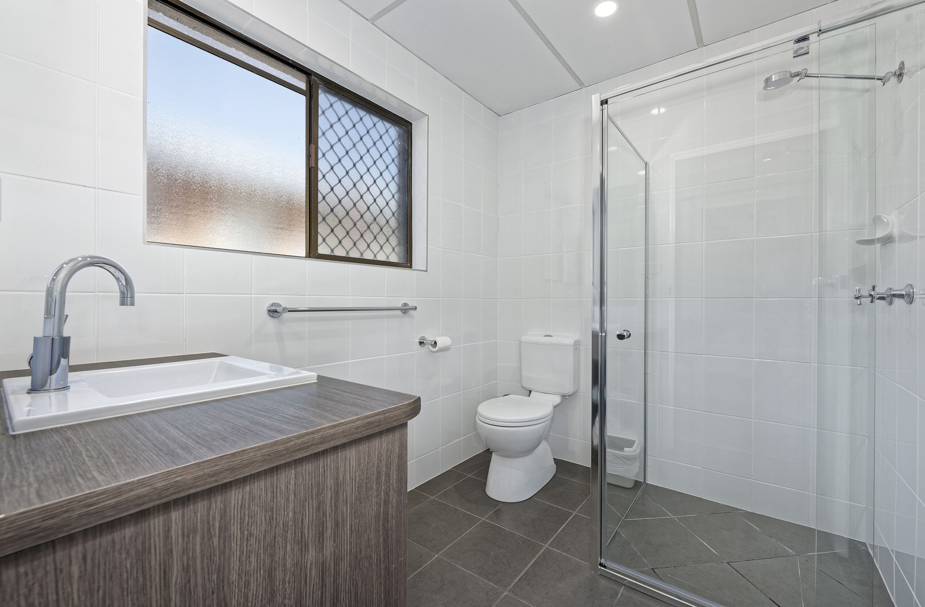 A modern bathroom with a shower, toilet, and sink.