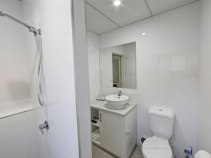 Een moderne badkamer met een glazen douchecabine, een wit wastafelmeubel en een toilet.