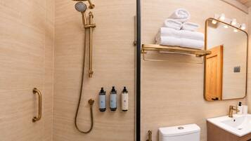 Un baño moderno con cabina de ducha, inodoro, lavabo y espejo con iluminación.