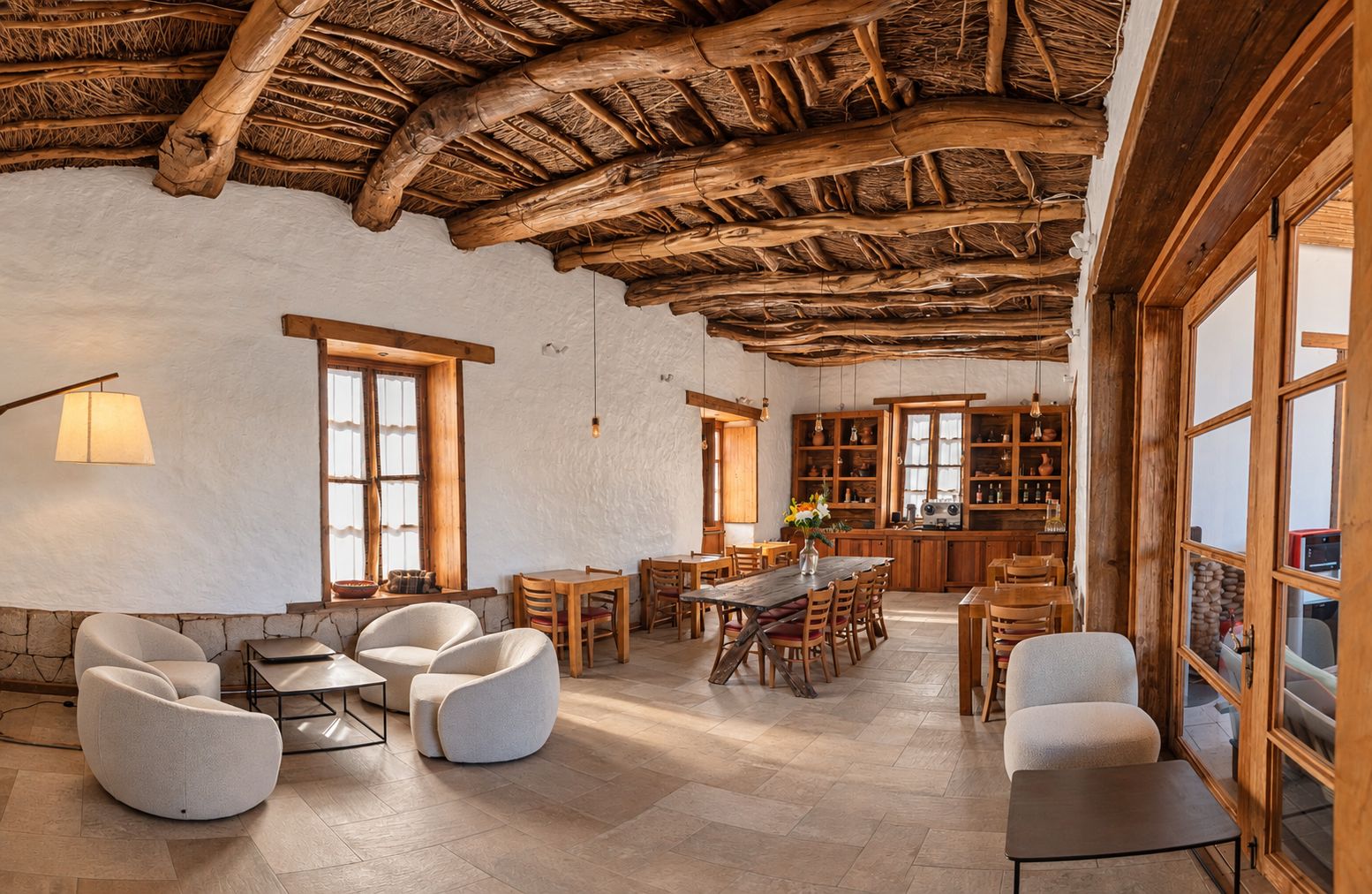 Um interior rústico com telhado de colmo, mobiliário de madeira e uma ampla área de cozinha.