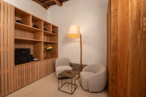 Ein gemütliches Zimmer mit einer Holzhülle, einem Flachbildfernseher, einer Lampe und zwei Sesseln.