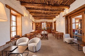 Een gezellig interieur met een rustiek houten plafond, een centraal gelegen eethoek en een keuken met houten kastjes.