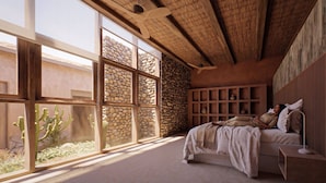 Une chambre avec une grande fenêtre, un lit, un plafond en bois et un mur en pierre.