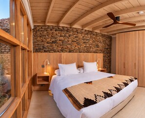 Ein Schlafzimmer mit Steinwand, Holzboden und einem Bett mit weißer Bettwäsche.