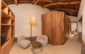 Ein gemütliches Zimmer mit Holzböden, einer Lampe, zwei Sesseln und einem kleinen Tisch.