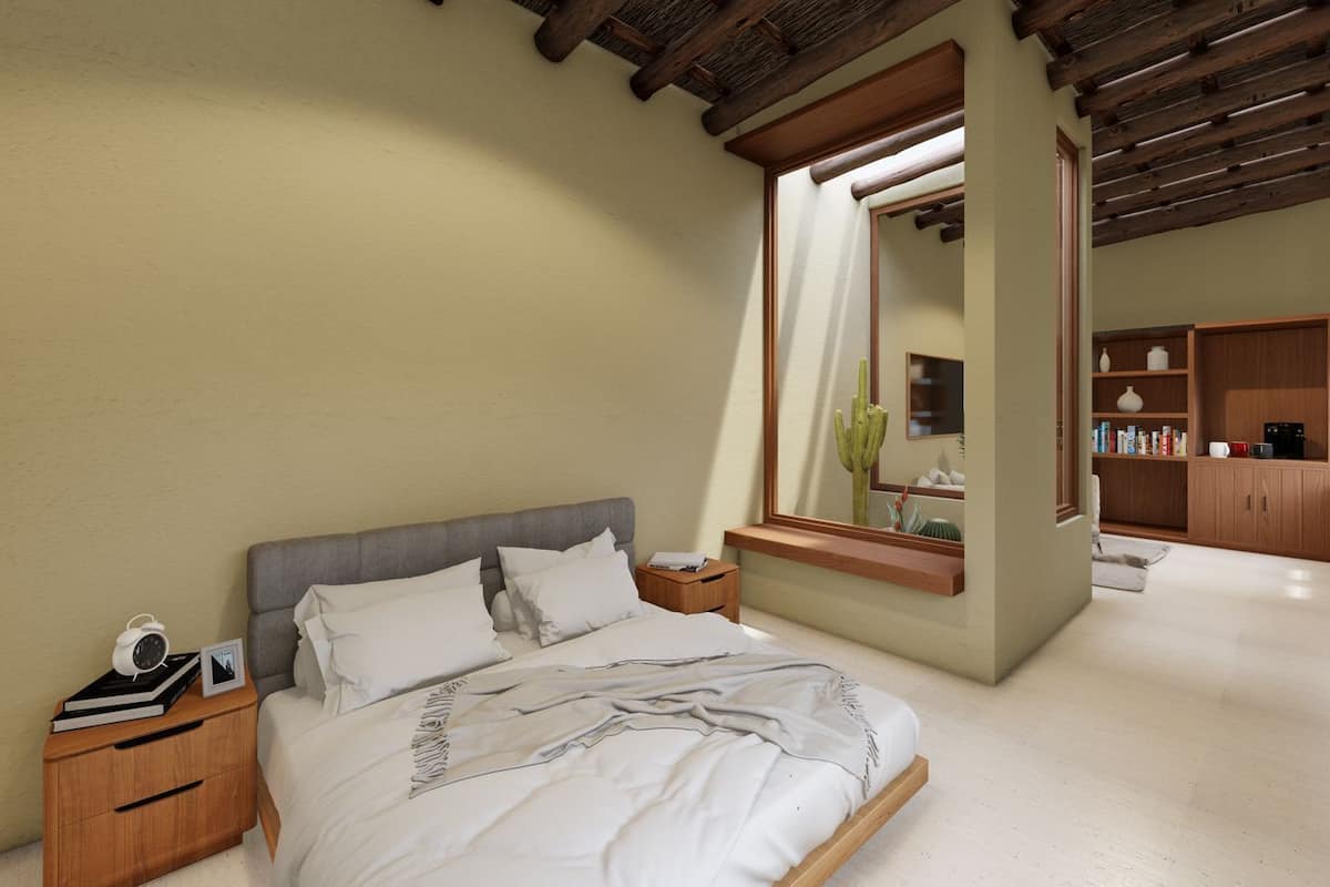 Ein Schlafzimmer mit Bett, Nachttisch und Schranken. Ein Fenster bietet Blick auf einen Kaktus, ein Spiegel ist ebenfalls vorhanden.