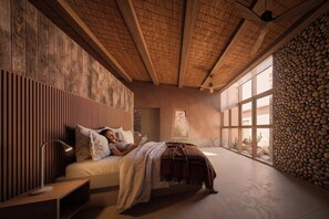Un dormitorio con cama, mesita de noche y un amplio ventanal con vista a un muro de roca.