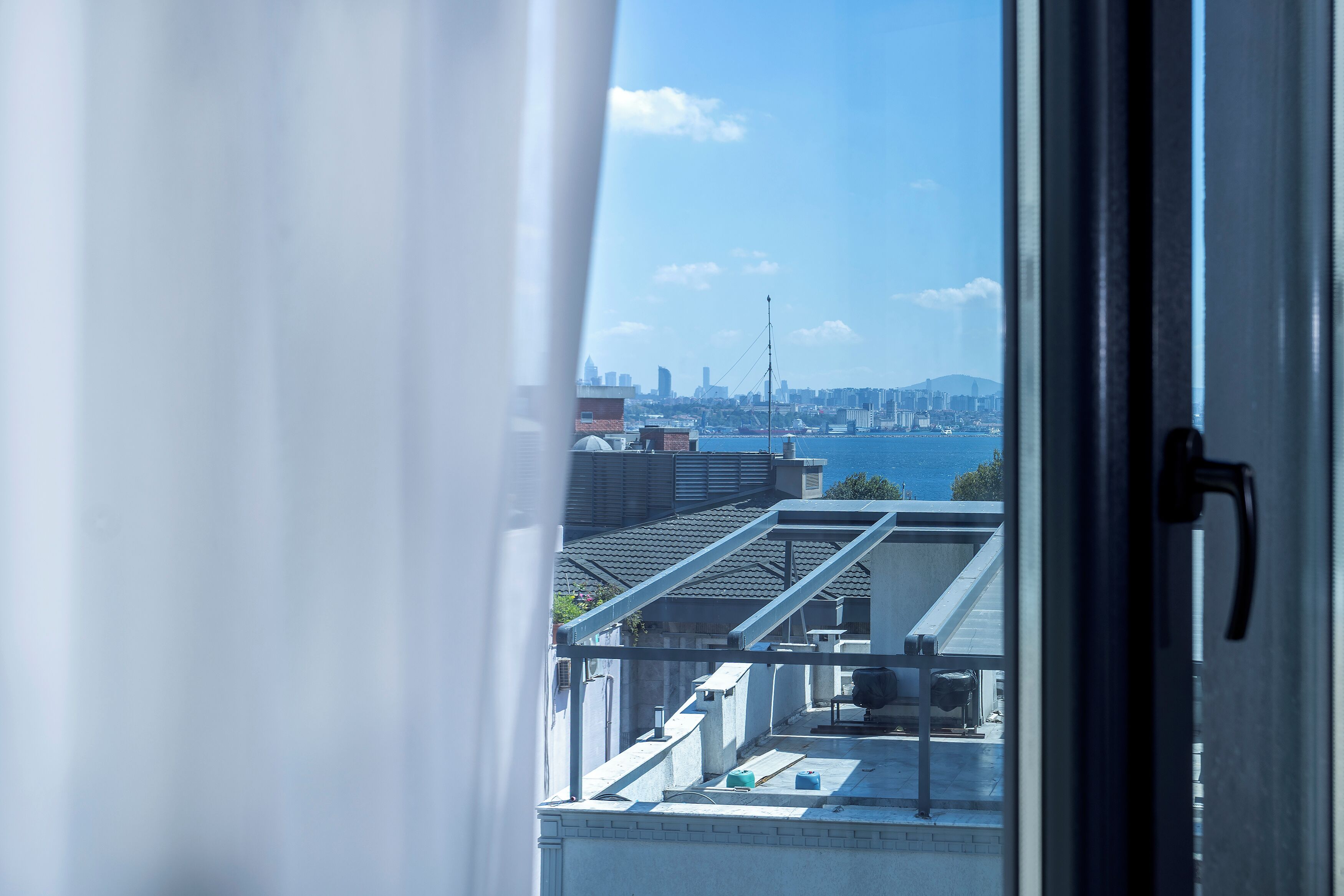A view from a window overlooking a cityscape with buildings and a body of water.