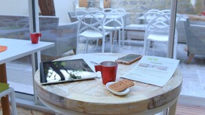 A round wooden table with a tablet, a red mug, a biscuit, and a menu. - Hôtel Villa Sorel (Boulogne-Billancourt)