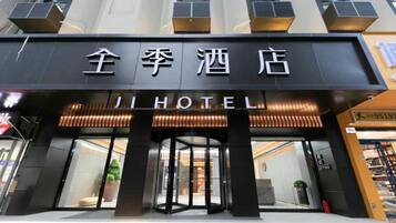 A hotel entrance with a revolving door and a sign that reads 'JI HOTEL'.