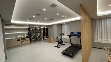 A modern hotel room with a kitchen, a treadmill, and a large window.