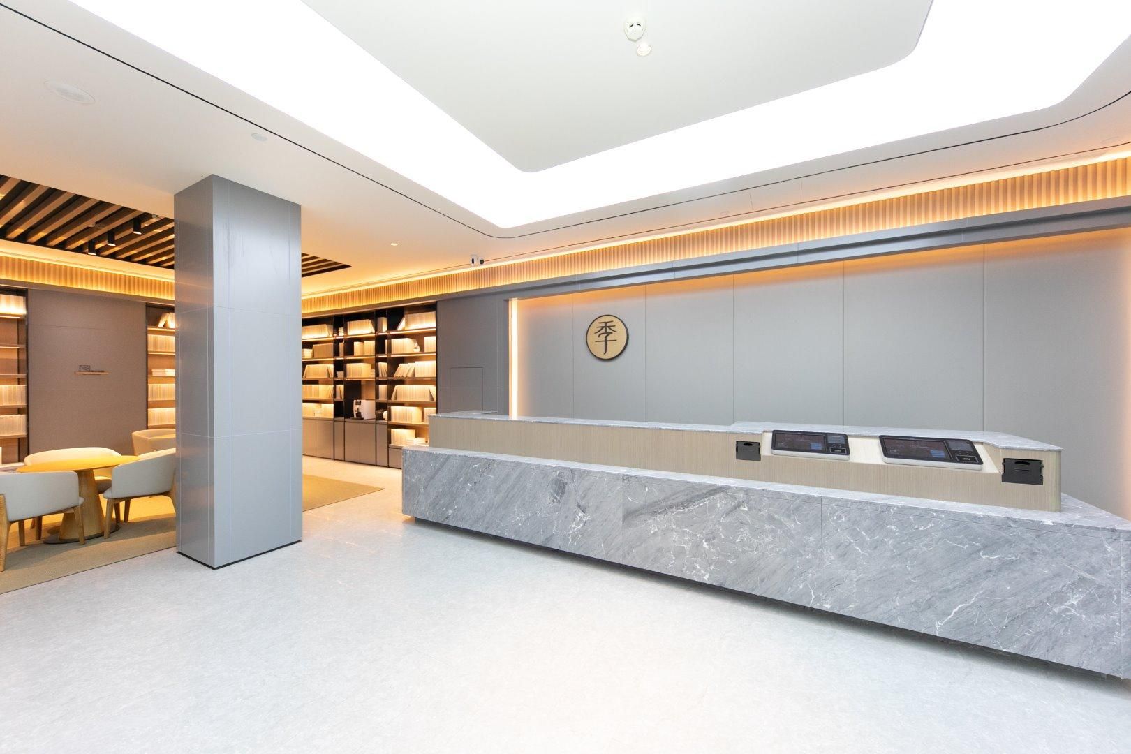 A modern reception desk with a marble top, a digital screen, and a wall-mounted sign.
