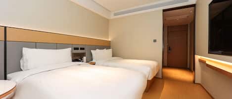 A hotel room with two beds, a bedside table, a TV, and a door leading to another room.