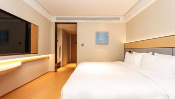 A hotel room with a large bed, a bedside table, a mirror, and a framed picture on the wall.