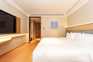 A hotel room with a large bed, a bedside table, a mirror, and a framed picture on the wall.