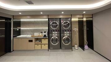 A modern bathroom with a sink, two wall-mounted washing machines, a toilet, and a shower area.