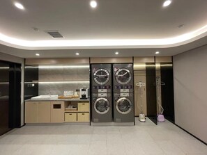 Un baño moderno con un lavamanos, dos lavadoras empotradas, un inodoro y una zona de ducha.