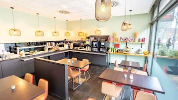 A cafe with a counter, seating area, and a view through the window.