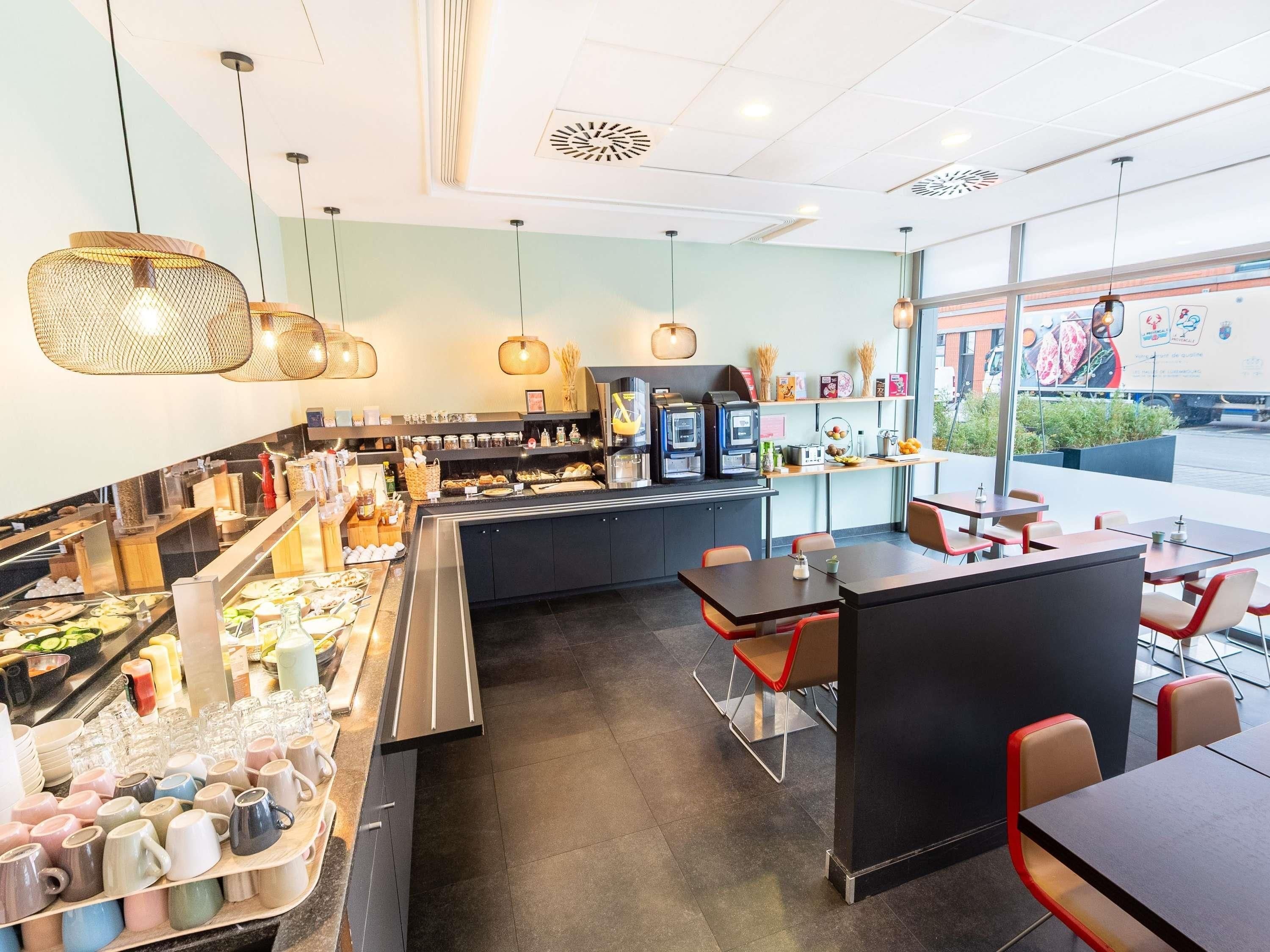 A modern cafe interior with a central counter, seating area, and a view of the street outside.