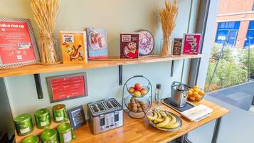 Un bufé de desayuno con cajas de cereales, un tostador y fruta fresca.