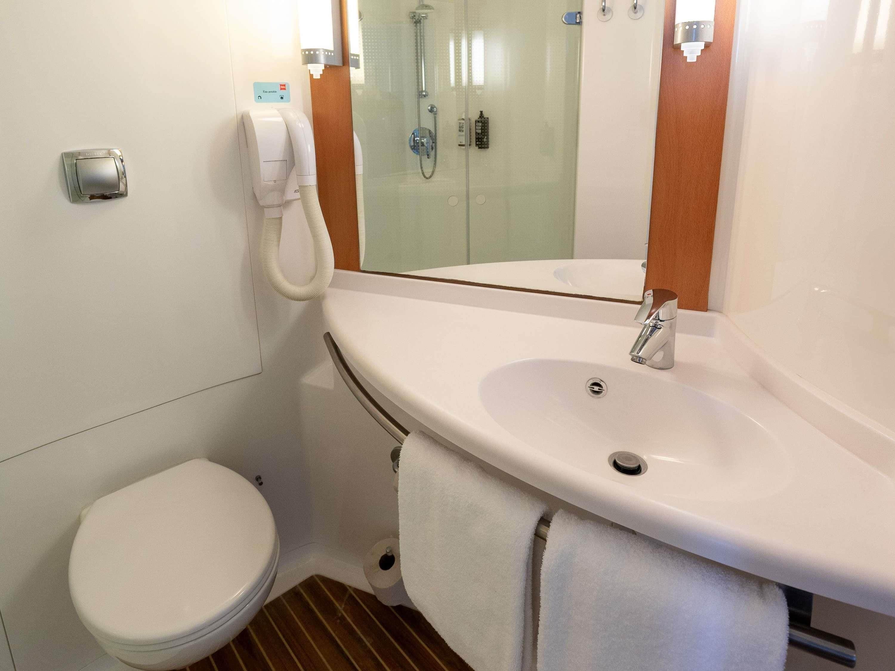 Een badkamer met toilet, wastafel met spiegel en douche.