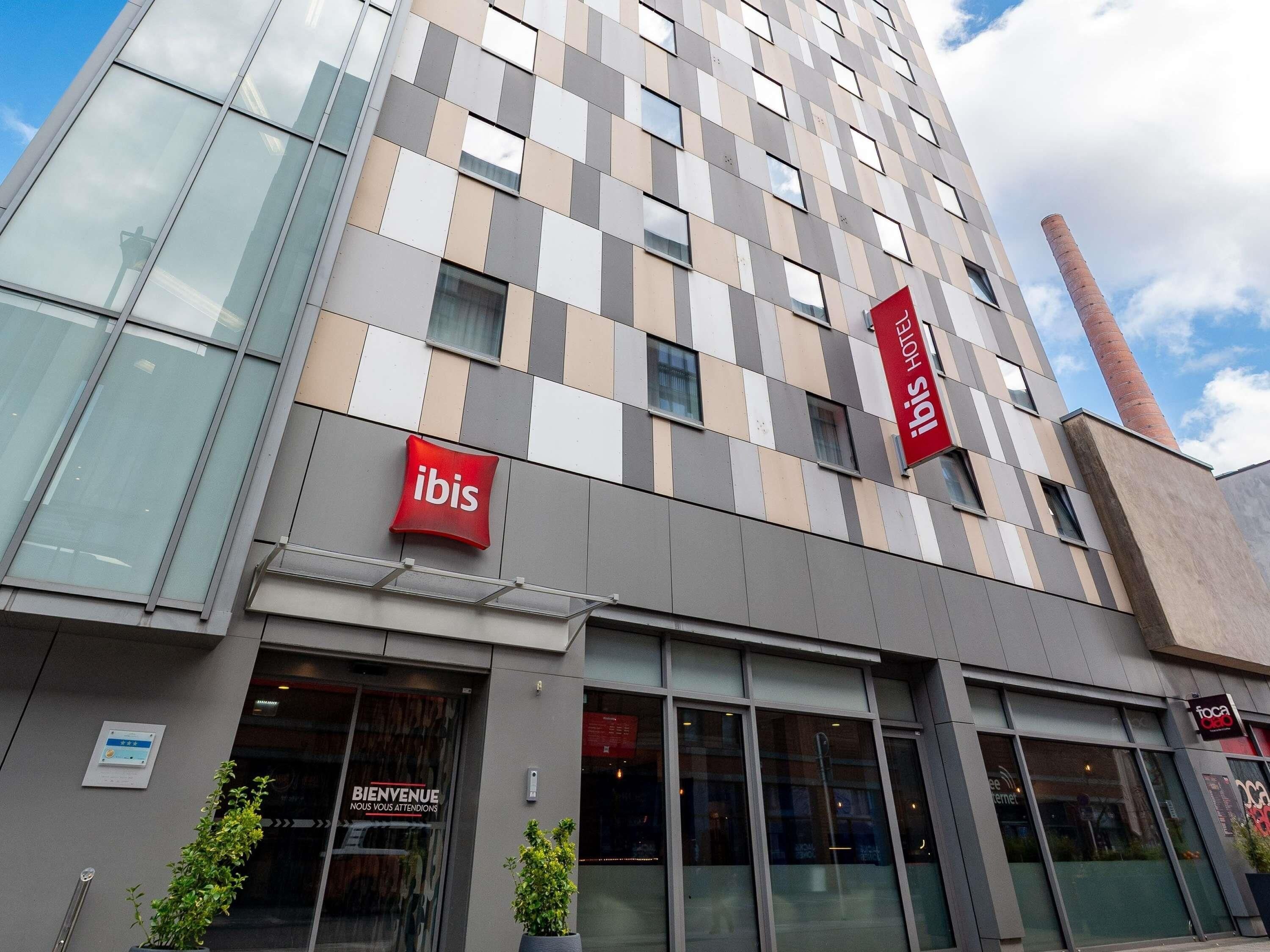A hotel with a modern facade, large windows, and signage for 'ibis' and 'hotel ibis'.