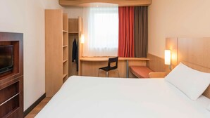 A hotel room with a bed, a desk, a chair, a TV, and a wardrobe. - ibis Esch Belval (Esch-sur-Alzette)