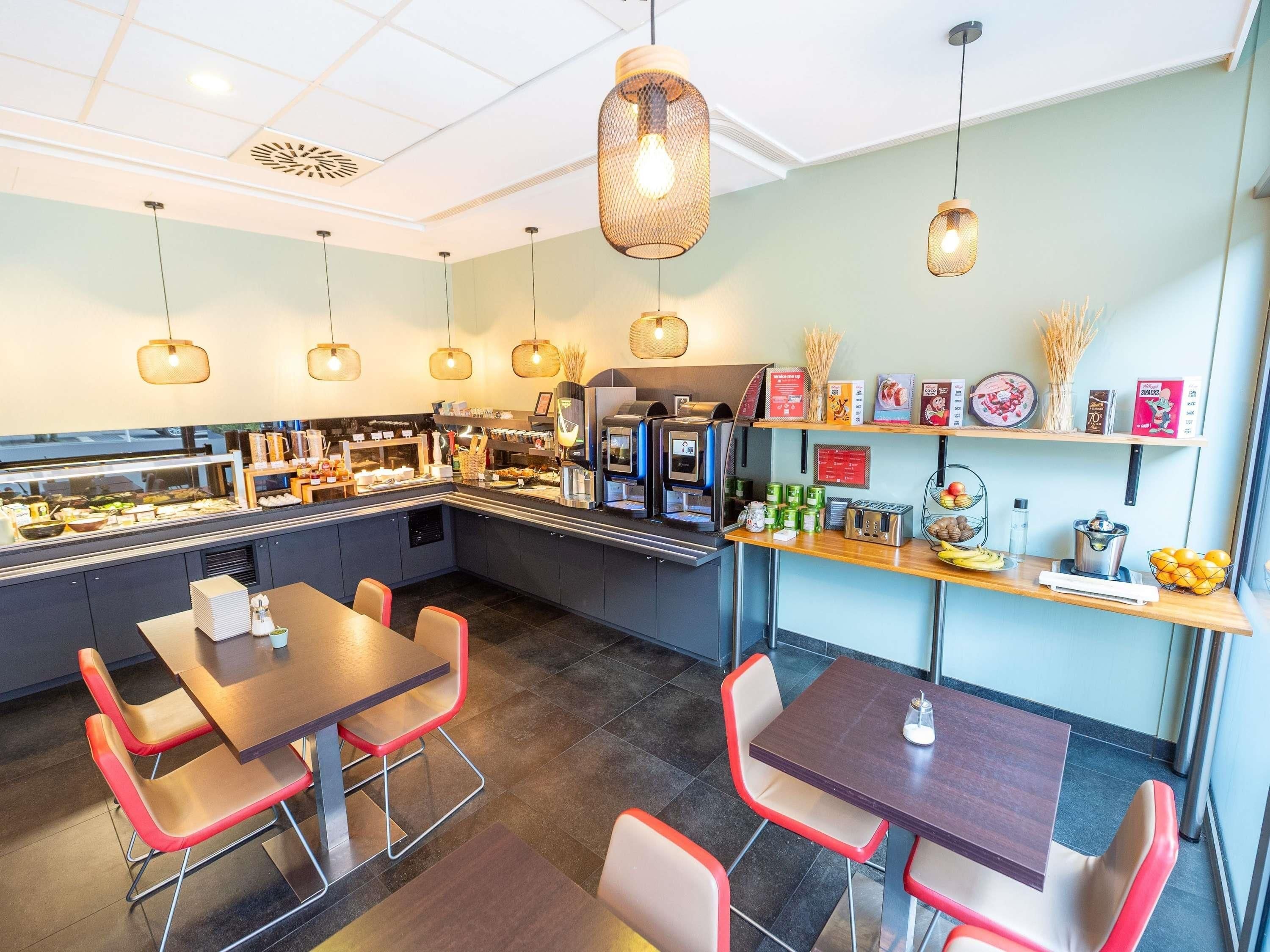 Cafetería con mostrador, zona de mesas y diferentes productos alimenticios a la vista.