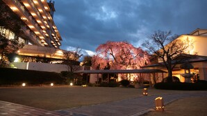 A hotel with a modern architectural design, featuring a large building with multiple balconies and a covered outdoor area with a cherry blossom tree. - Hyoe Koyokaku (Kobe)