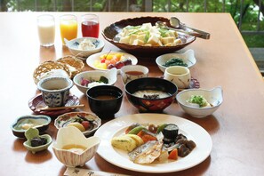 Una mesa dispuesta con diversos platos, incluyendo un bol de tofu, una bandeja de verduras y varios recipientes pequeños con diferentes alimentos.