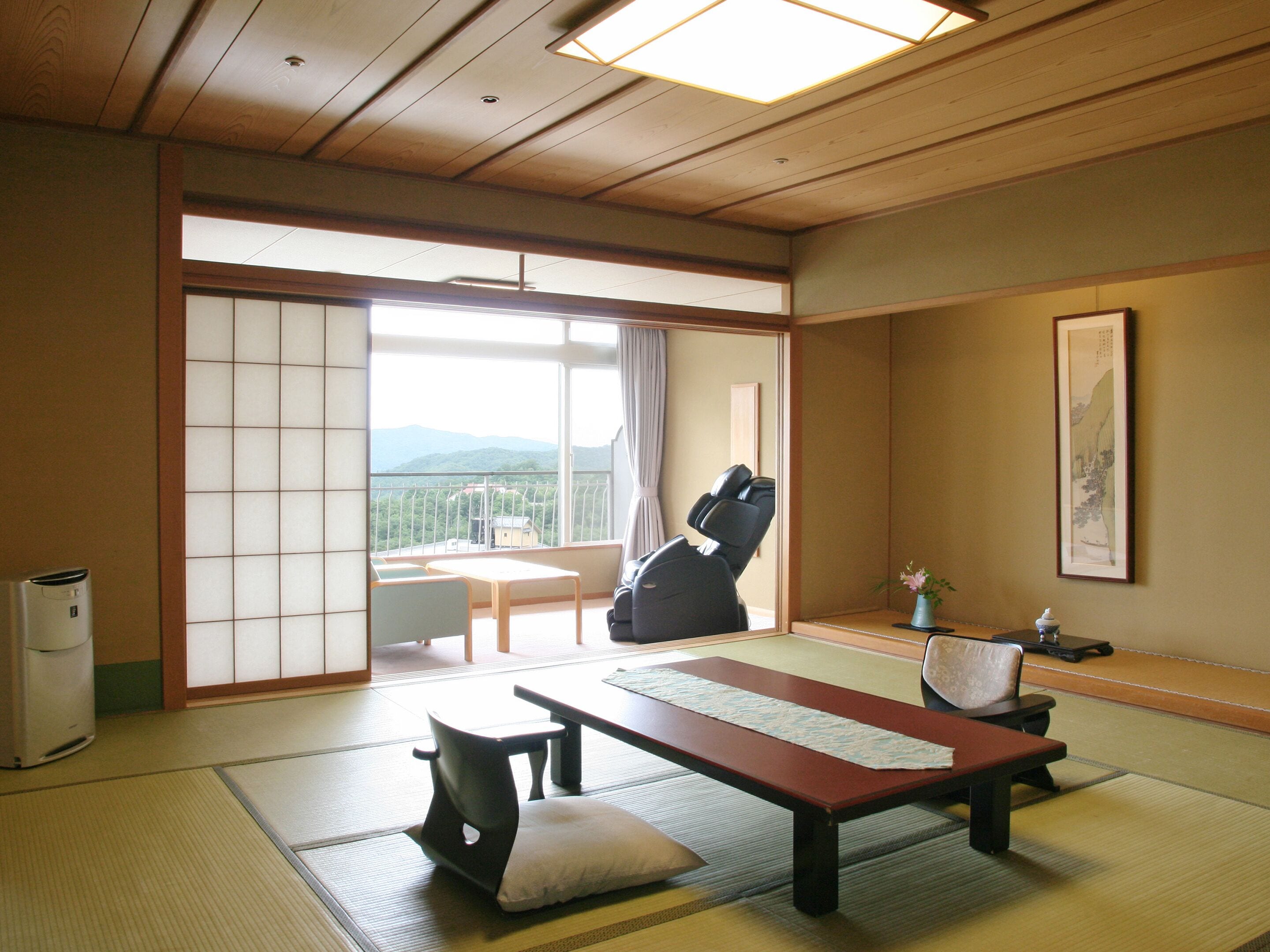 Une pièce de style japonais traditionnel, avec un sol recouvert de tatamis, une table basse, un canapé et un fauteuil de massage.