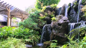 A waterfall cascading over rocks surrounded by lush greenery. - Hyoe Koyokaku (Kobe)