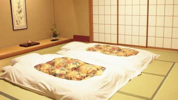 A traditional Japanese room with tatami flooring, a low wooden bed with white bedding, and a shoji screen in the background.