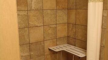 Una ducha con cortina blanca, estante metálico y pared con azulejos.
