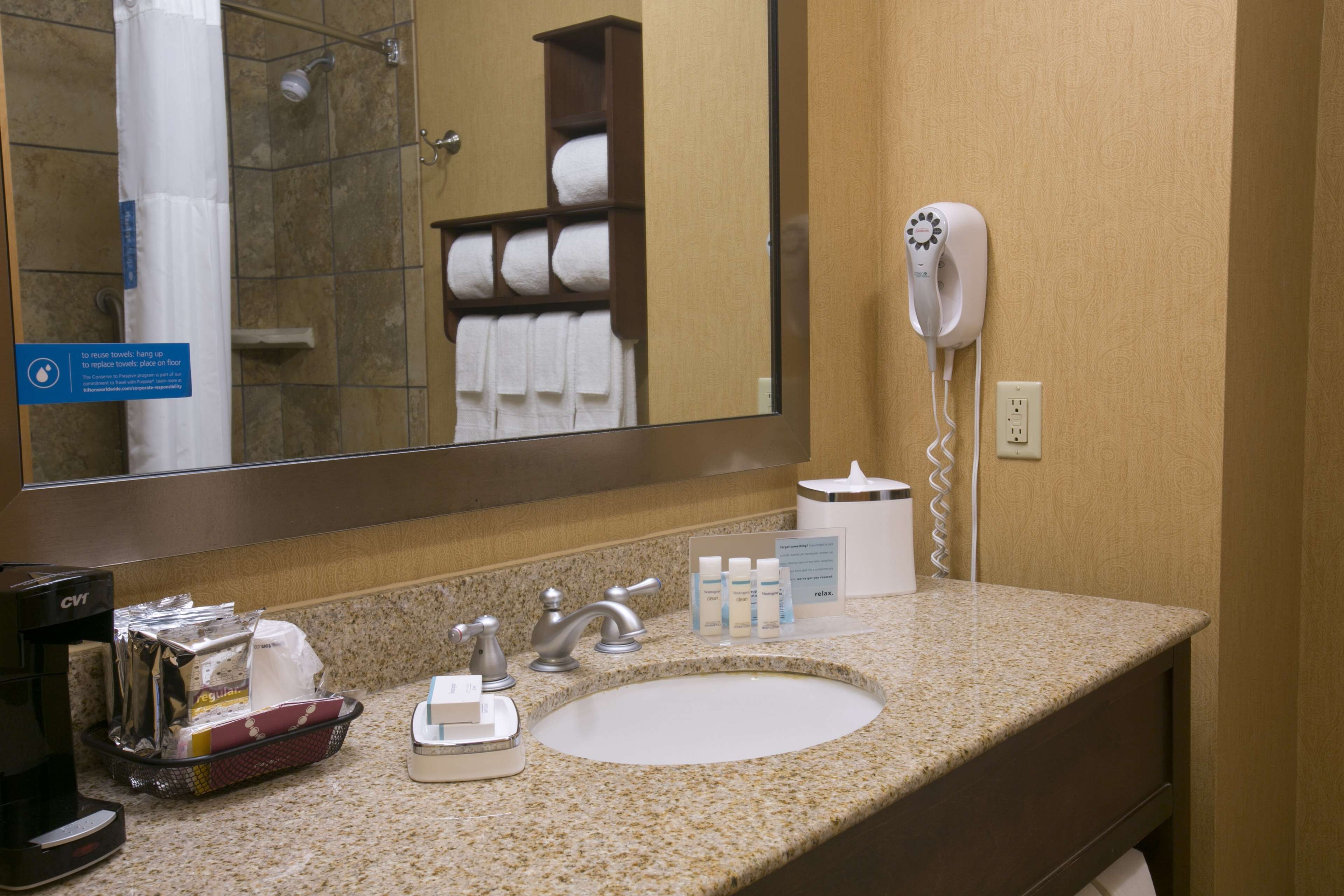 A hotel bathroom with a sink, a hand dryer, and a towel rack.