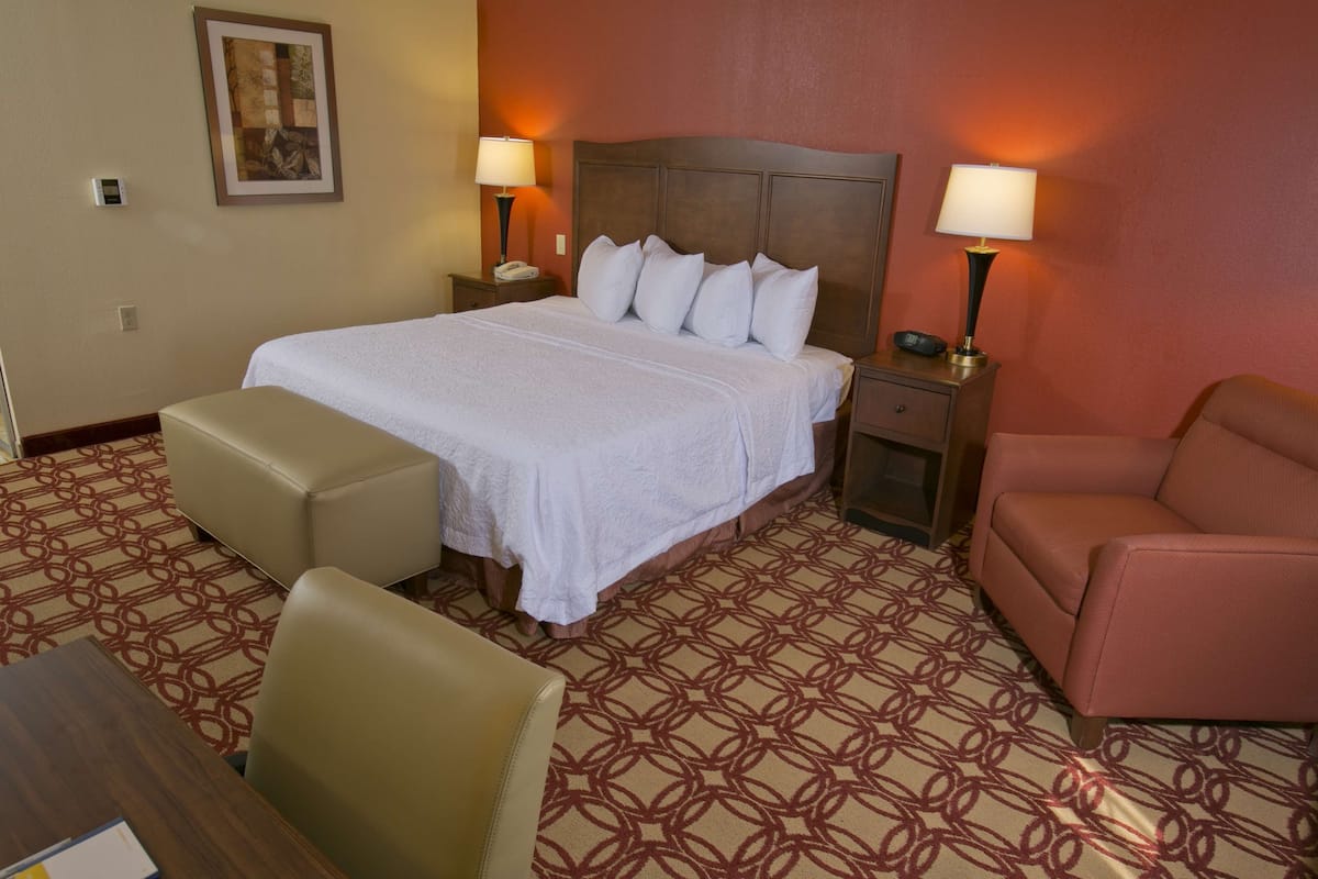 A hotel room with a large bed, two bedside tables with lamps, a small sofa, and a patterned carpet.