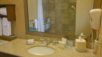 A hotel bathroom with a sink, mirror, towel rack, and a hand dryer.