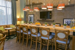 A dining area with a long wooden table, six chairs, and a TV mounted on the wall. - Hampton Inn & Suites Wiggins (Wiggins)